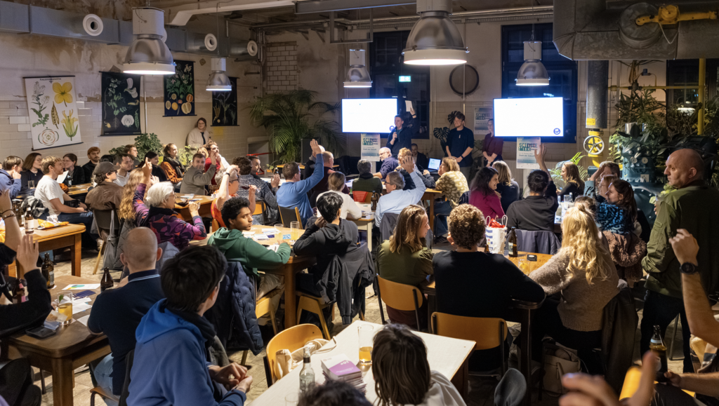 Menschen sitzen in einer gemütlichen Kneipe und lauschen einem Vortrag und stellen Fragen