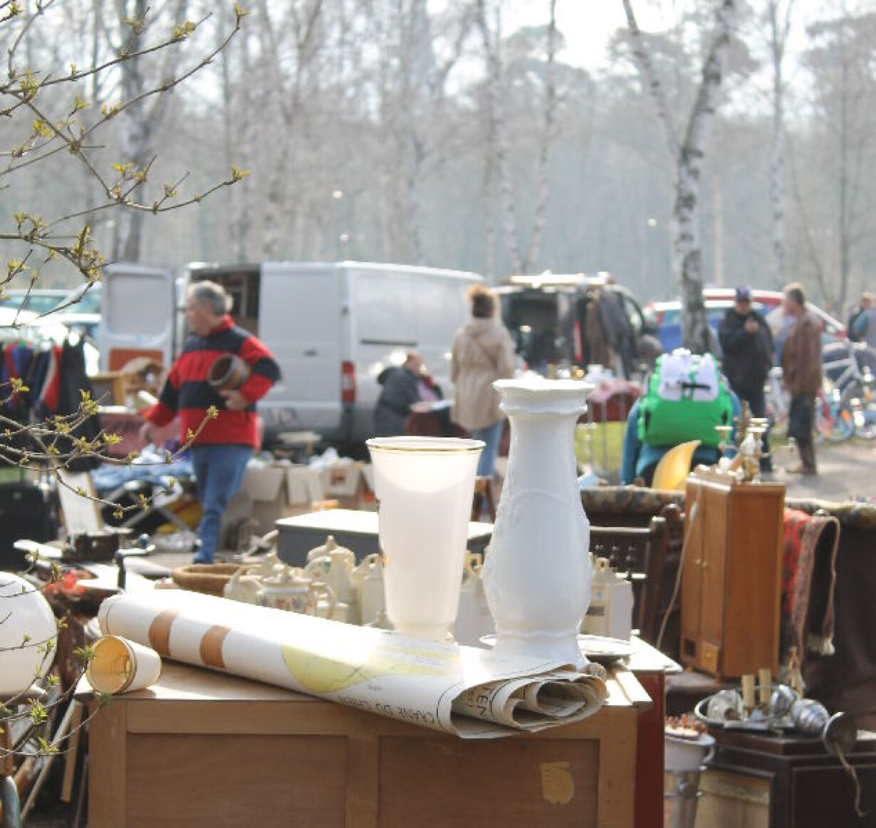 Flohmarkt im Freien mit verschiedenen Antiquitäten und Haushaltsgegenständen auf Tischen.