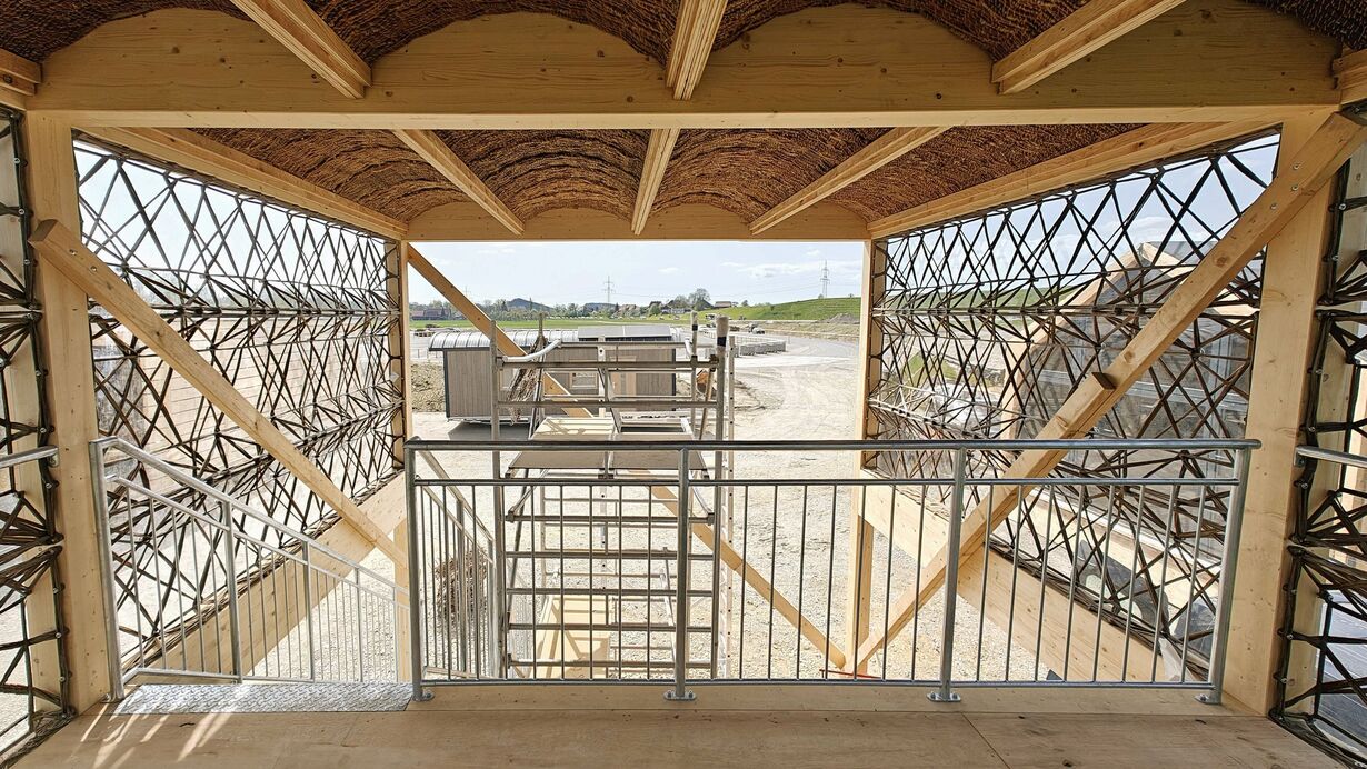 Innenansicht einer Holz- und Metallkonstruktion mit seitlicher Gitterbefestigung auf Baustelle.